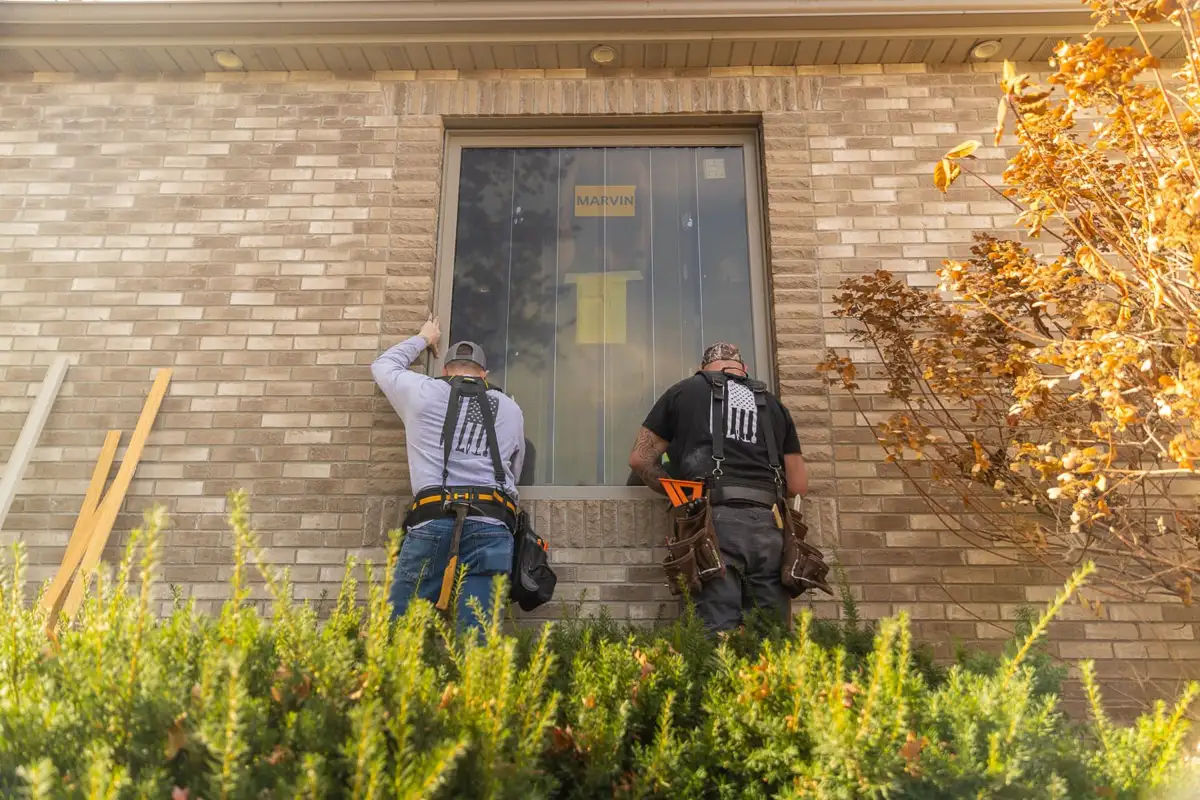 Two men installing a window on a home